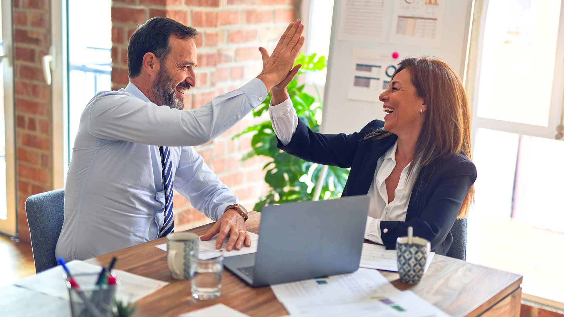 Business professionals celebrating a successful IT partnership - Waib3 Technologies